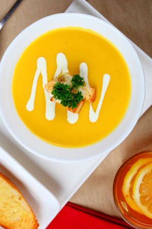 Single pumpkin soup and bread in dish on the table.