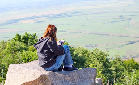 Relaxed young woman,sitting on a rock with phone.の写真素材