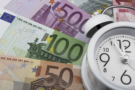Euro notes and a clock. Business concept. Time is money. (50, 100 and 500 EUR)の写真素材