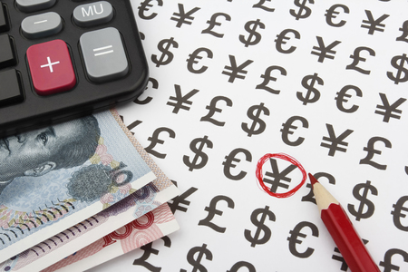 Calculator on top of 3 Chinese banknotes, a red pencil in the left side of the picture pointing at a Yuan sign.の写真素材