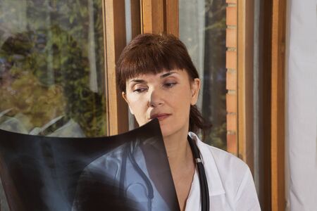 doctor examines a radiograph near a windowの写真素材