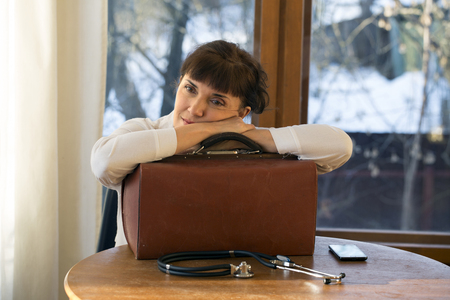 Tired doctor leaning on suitcaseの写真素材