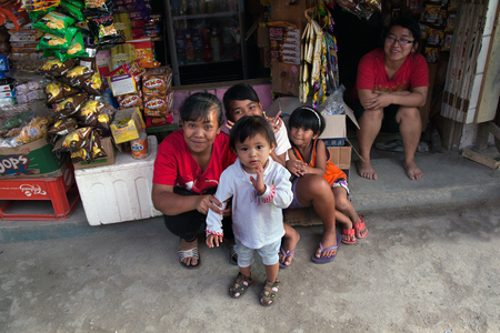 MEDAN,INDONESIA - AUGUST 18,2012: Women and children are sitting near the storefrontのeditorial素材