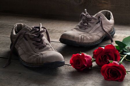 Men's shoes and red roses on the wooden floorの写真素材