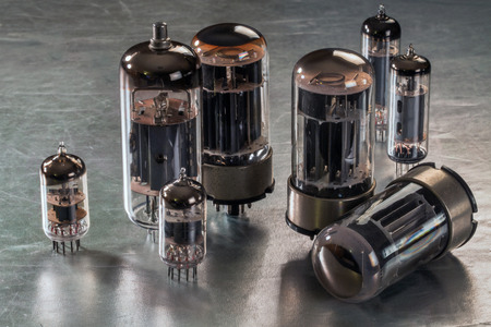 Radio tubes of different sizes lie on a metal surfaceの写真素材