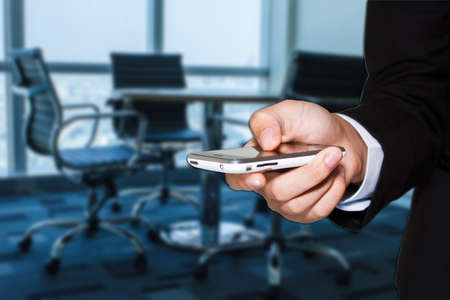 Close up of a man using mobile in office for businessの写真素材