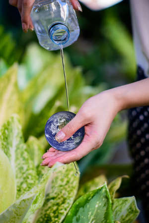 Young woman`s hands holding earth and sprinkle water on earth. Ecology concept. Elements of this...