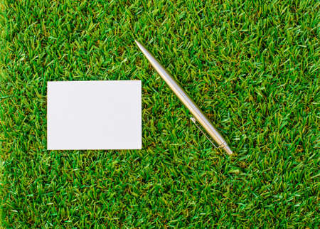 white paper with a pen over lush green grassの写真素材