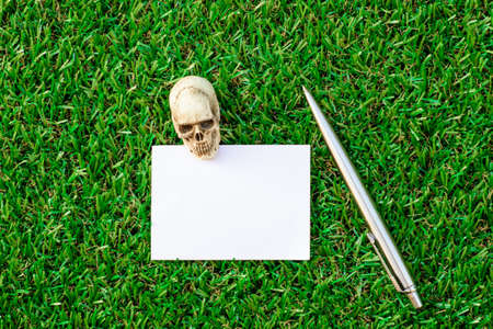 white paper with a pen over lush green grassの写真素材