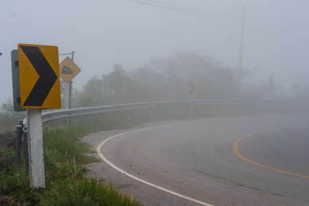 Road Signs warn Drivers for Ahead Dangerous Curve with fog.の写真素材