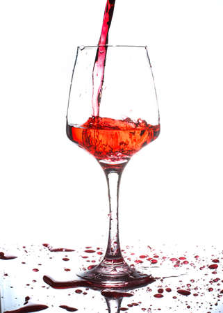 red wine pouring into wine glass isolated on whiteの写真素材