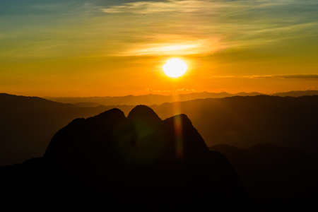 Sun setting over hills in Thailandの写真素材