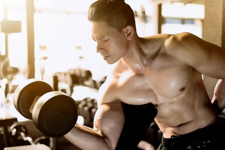 Muscular bodybuilder man doing exercises with dumbbellsの写真素材