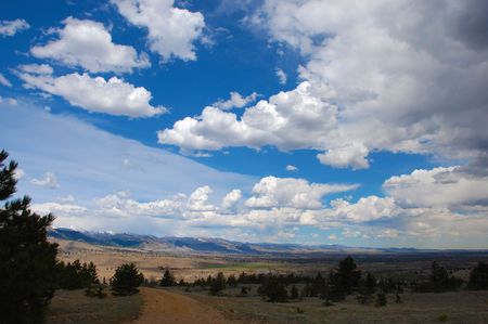 A dirt road leads into a sweeping scenic valley with a distant city