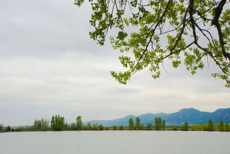 Open and spacious view across a small lake of trees, mountains and skyの写真素材