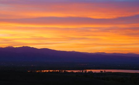 Colorful and spectacular sunset over purple mountains' majesty, reflected brightly in a distant lake.の写真素材