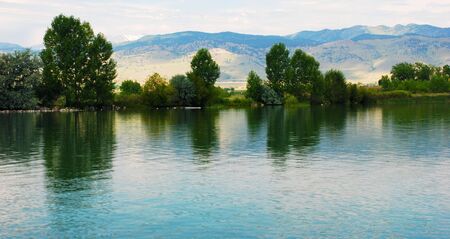 Quiet reflections in a rippling lake on a peaceful dayの写真素材
