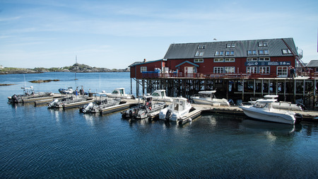 Reine, Norway - June 2, 2016: Traditional fishing boat with red rorbu fishing houses on Lofoten islands in Norwayのeditorial素材