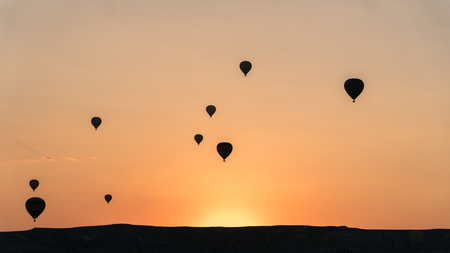 Cappadocia, Turkey - August 2017: Silhouettes of hot air balloons flying above rocky landscape in Cappadocia, Turkeyの写真素材