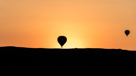 Silhouettes of hot air balloons flying above rocky landscape in Cappadocia, Turkeyの写真素材