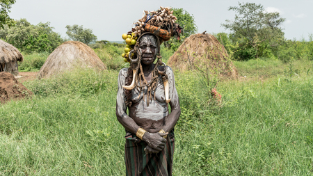 Mago National Park, Omo River Valley, Ethiopia - September 2017: Portrait of a Mursi woman. The women of the Mursi tribe have a lip plate and iron decorationsのeditorial素材