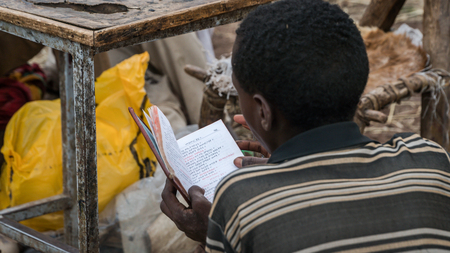 Lalibela, Ethiopia - September 2017: Unidentified pilgrim reading bible at one of the old rock churches from Lalibelaのeditorial素材