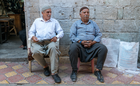 Adiyaman, Turkey - July 2018: Unidentified men sitting on stools chatting in Adiyaman city historical old Oturakci bazaar inside the old city, Turkeyのeditorial素材