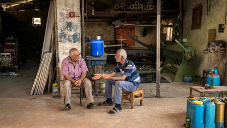 Adiyaman, Turkey - July 2018: Unidentified men sitting on stools chatting in Adiyaman city historical old Oturakci bazaar inside the old city, Turkeyのeditorial素材