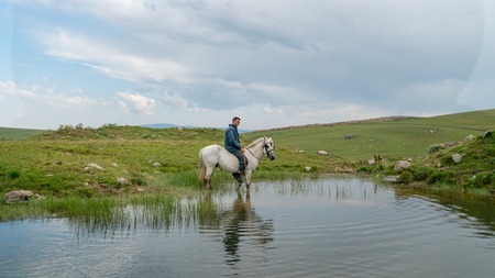 Artvin, Turkey - July 2018: Man riding a horse inside a small pondのeditorial素材