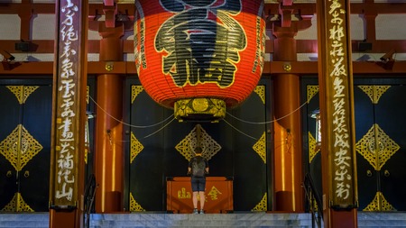 Tokyo, Japan - August 2018: Unidentified man praying under the big red lantern of Sensoji Kannon Asakusa templeのeditorial素材