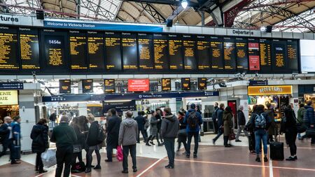 London, United Kingdom - Jarnuary 2019: Passengers looking at the timetable on electronic board in Victoria station is a central London railway terminus and connected to Undergroundのeditorial素材