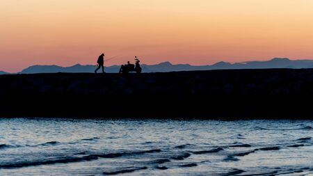 Unidentified people silhouette walking on the pier during sunsetの写真素材