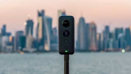 Doha, Qatar - February 2019: Insta360 One X 360 camera on a tripod with cityscape in the background