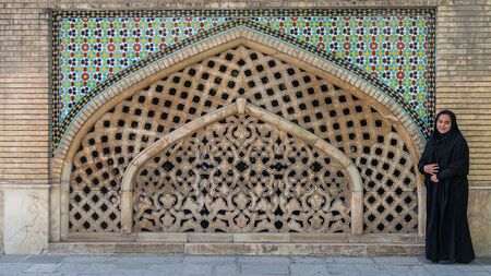 Tehran, Iran - May 2019: An Iranian woman standing against a tiled wall in the courtyard of Golestan palace, a UNESCO world heritage siteのeditorial素材