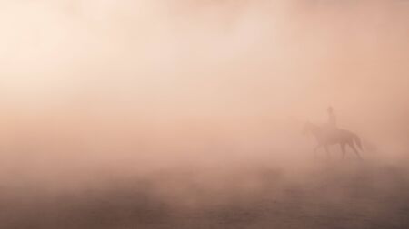 Kayseri, Turkey - November 2019: Unidentified man riding a horse in dust and fogの写真素材