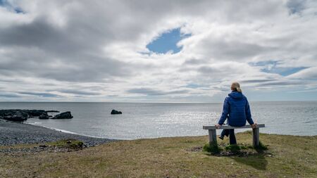 Djupalonssandur, Iceland - August 2019: Unidentified woman looking at volcanic lava rocks at Djupalonssandur beach in Snaefellsnes peninsula in Western Icelandの写真素材