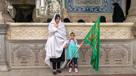 Shrine of Fatima Masumeh, Qom, Iran - May 2019: Iranian women and her daughter holding an islamic banner inside Shrine of Fatima Masumeh in Qomのeditorial素材