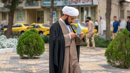 Qom, Iran - May 2019: Iranian man checking his mobile phone in a street in the sacred city of Qomのeditorial素材