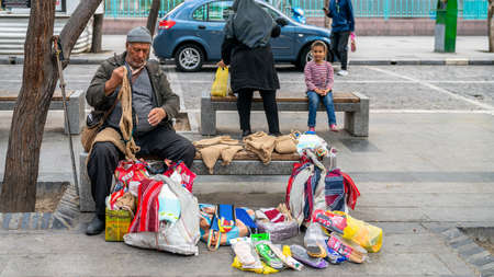 Tehran, Iran - May 2019: Iranian man selling stuff on a bench in Tehran city center