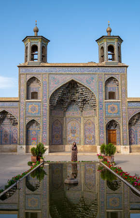Shiraz, Iran - May 2019: Woman standing in the courtyard with pool of Nasir al-Mulk Mosque in Shiraz