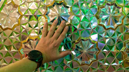 Shiraz, Iran - May 2019: Hand touching the interior decoration of mirrors in Shah e Cheragh Shrine
