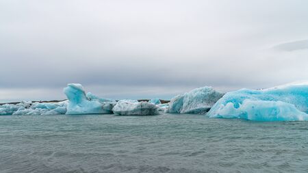 View of icebergs in Jokulsarlon glacier lagoon formed with melting ice, Iceland, global warming and climate change conceptの写真素材