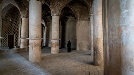 Isfahan, Iran - May 2019: Unidentified iranian woman in hijab black dress walking along the ancient...