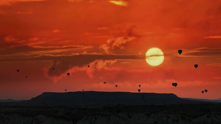 Silhouettes of hot air balloons flying in Cappadocia landscape with dramatic morning sky, Turkeyの写真素材