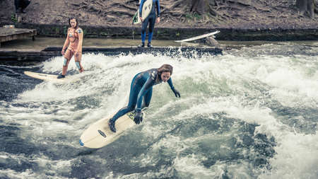 Munich, Germany - April 2014: Sport woman surfing on famous artificial river wave in Englischer garten, Munich, Germany.のeditorial素材