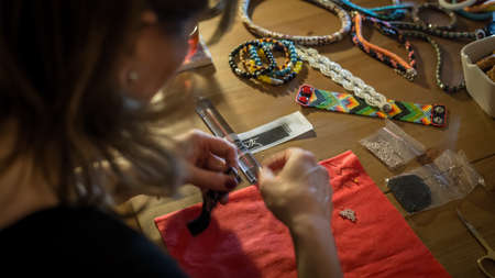 Istanbul, Turkey - April 2015: Woman making handmade jewelry with her tools and beads on wooden tableのeditorial素材