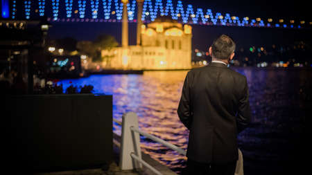Istanbul, Turkey - June 2014: Unidentified man watching Ortakoy mosque and July 15th Martyrs' bridge at nightのeditorial素材