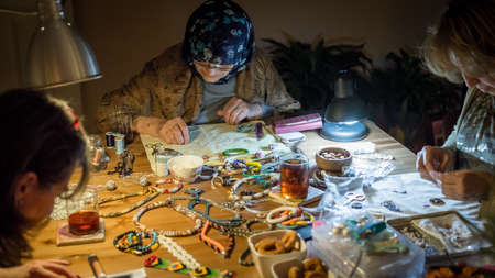 Istanbul, Turkey - April 2015: Group of women making handmade jewelry with her tools and beads on wooden tableのeditorial素材