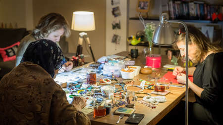 Istanbul, Turkey - April 2015: Group of women making handmade jewelry with her tools and beads on wooden tableのeditorial素材