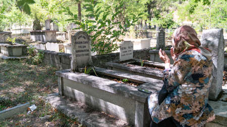Istanbul, Turkey - October 2012: Muslim woman praying by the graves in a cemetery